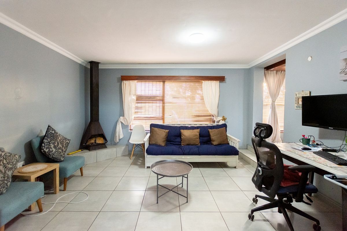 A spacious living room featuring light-colored floor tiles, crown molding, and a built-in freestanding fireplace, offering a comfortable and functional living space.