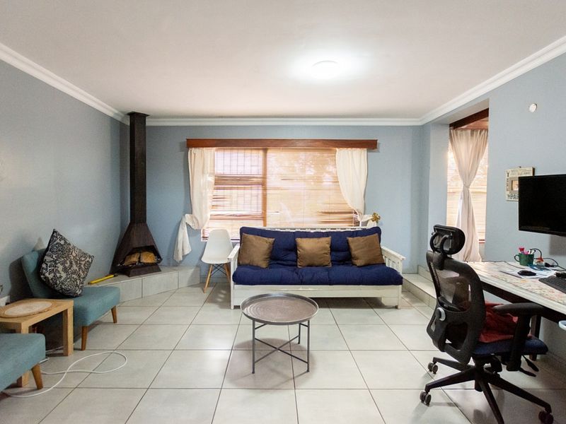 A spacious living room featuring light-colored floor tiles, crown molding, and a built-in freestanding fireplace, offering a comfortable and functional living space.