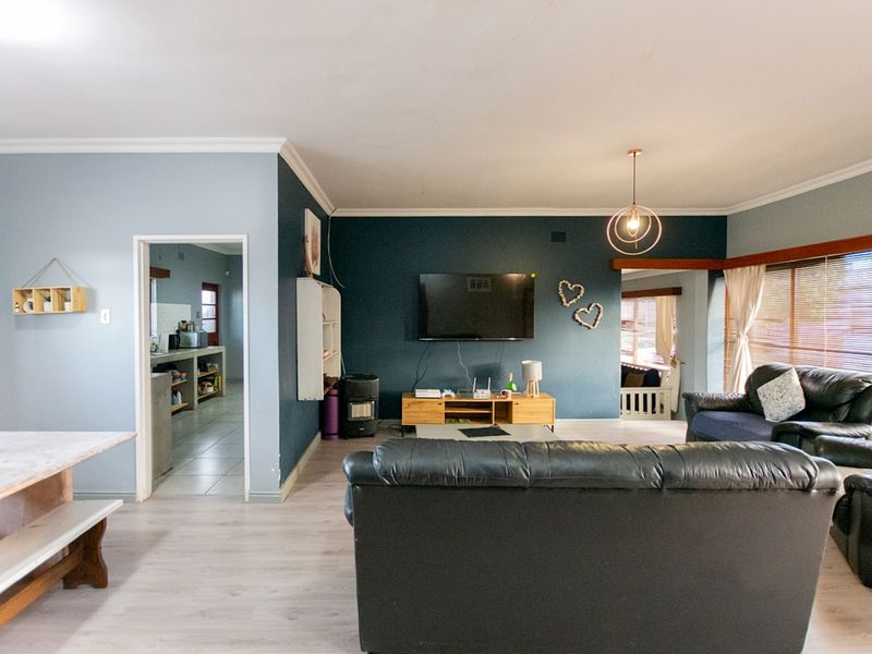 Open-plan living area featuring a dark accent wall, laminate flooring, and direct access to the kitchen and adjacent living spaces.