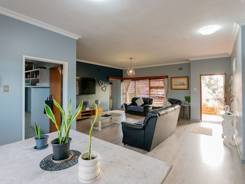 Spacious open-plan living area featuring light-toned laminate flooring, neutral wall finishes, and direct access to the exterior entrance.