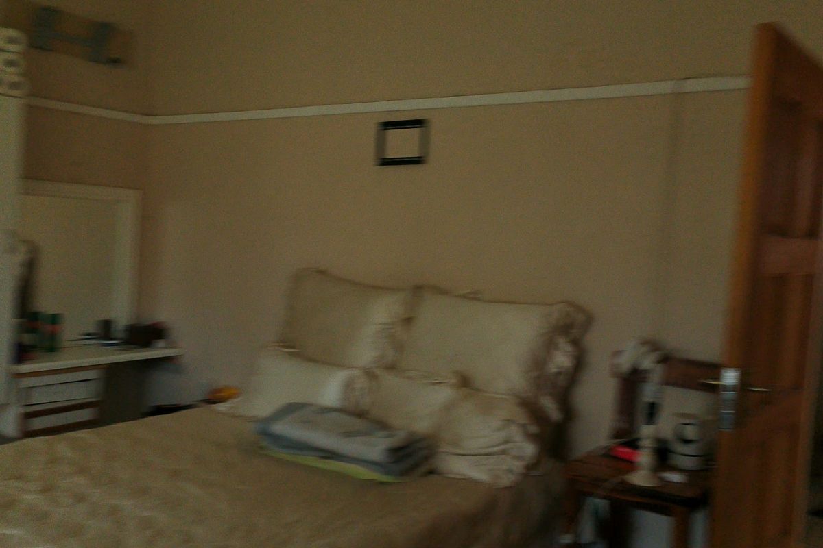 A bedroom featuring a built-in vanity unit, timber door, and picture rail, with an adjoining bathroom visible.