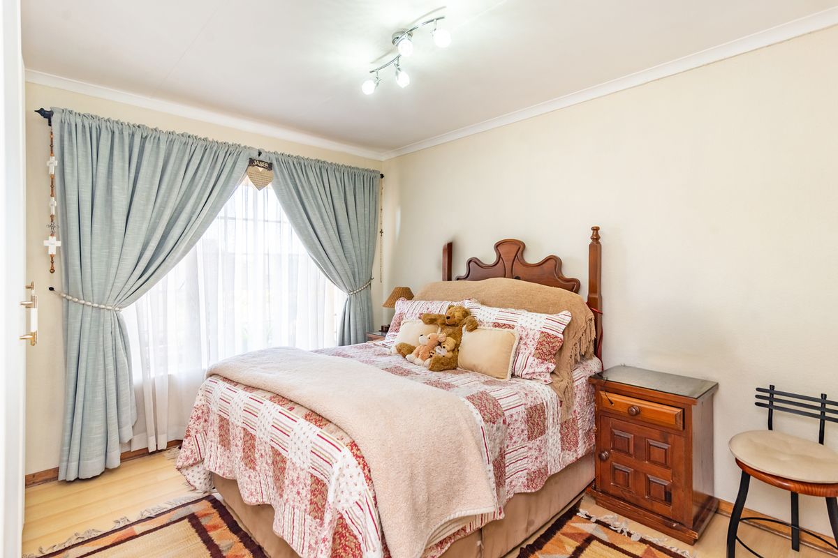 A well-lit bedroom featuring laminate flooring and a modern ceiling-mounted spotlight fixture, providing a comfortable and functional living space.