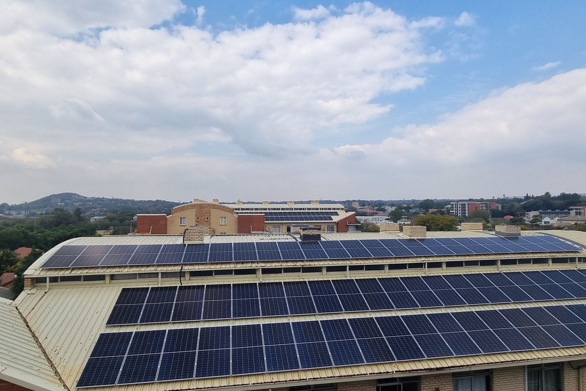 Aerial view of a residential building roof featuring an extensive installed solar panel array.