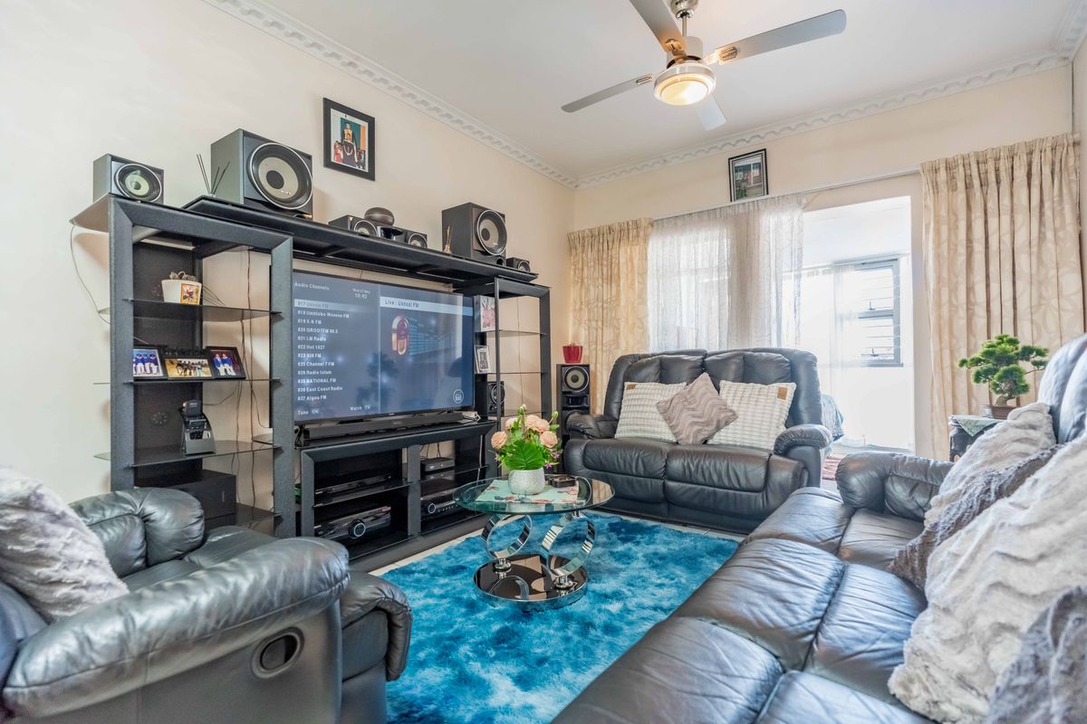 A comfortable living room featuring a ceiling fan, decorative cornice detailing, and direct access to an outdoor area through sliding glass doors.