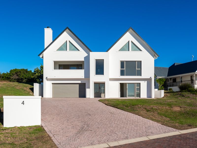 Modern double-story residential home featuring a paved driveway, integrated garage, and clean architectural lines with triangular gable windows.
