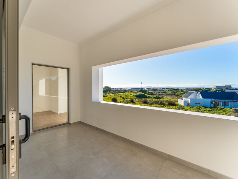 A modern covered balcony featuring tiled flooring and a large open window frame offering expansive views of the surrounding landscape and neighborhood.