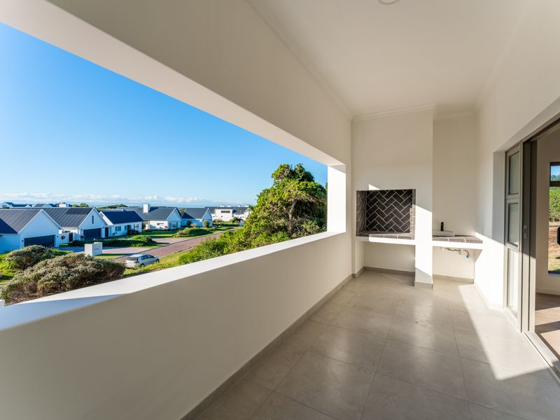 A covered balcony featuring a built-in braai, tiled flooring, and expansive views of the surrounding estate.