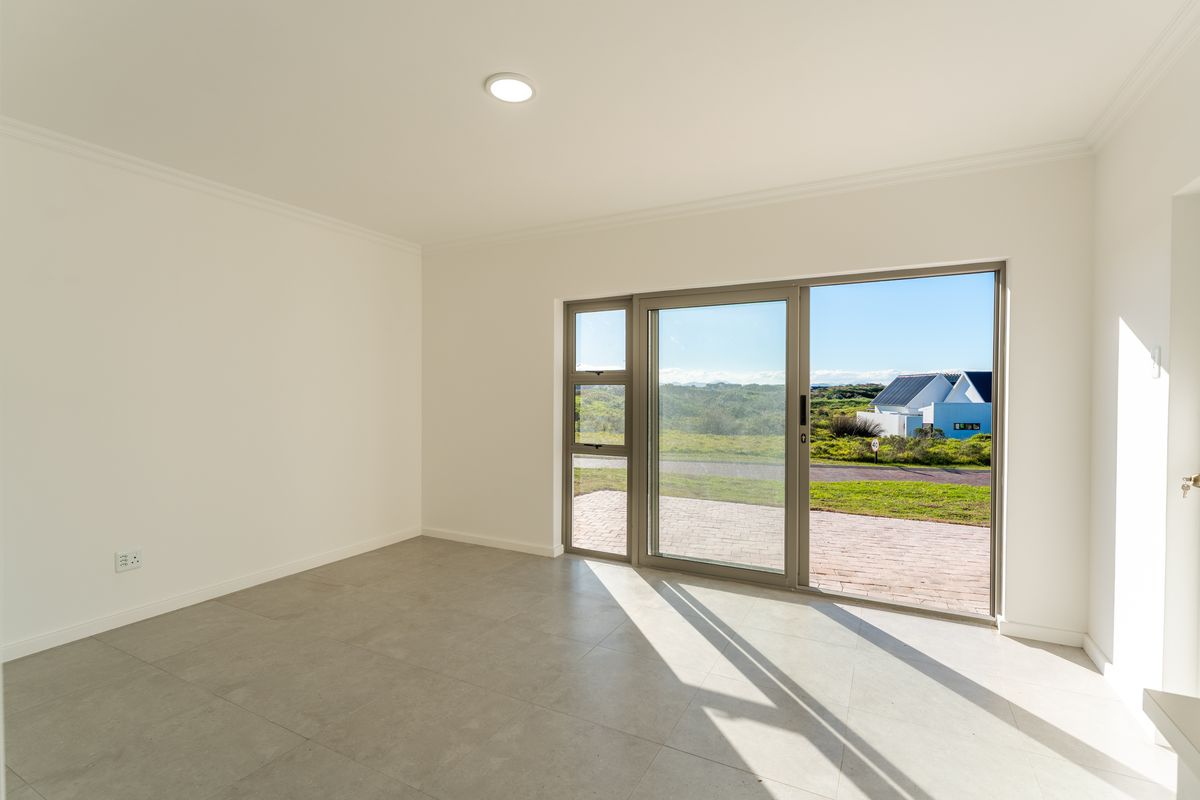A bright, empty room featuring large sliding glass doors that provide natural light and access to the exterior, finished with neutral floor tiles.