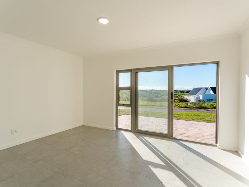 A bright, empty room featuring large sliding glass doors that provide natural light and access to the exterior, finished with neutral floor tiles.