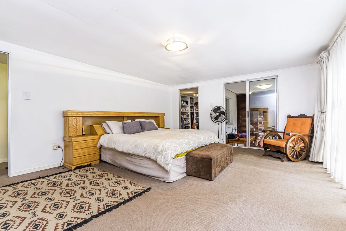 Spacious bedroom featuring neutral walls, carpeted flooring, a built-in wardrobe, and sliding glass doors providing access to an outdoor area.