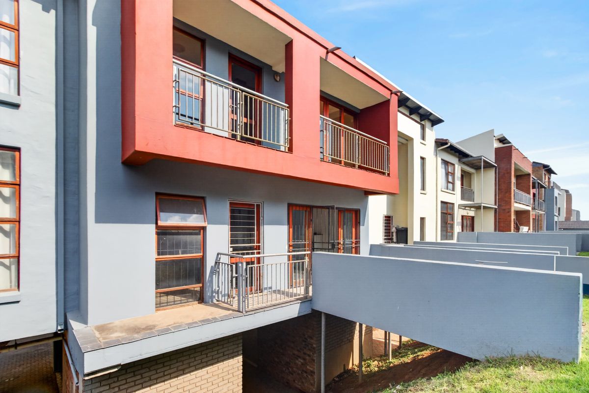 Rear elevation of a modern apartment building featuring private balconies with metal railings and direct access via sliding doors.