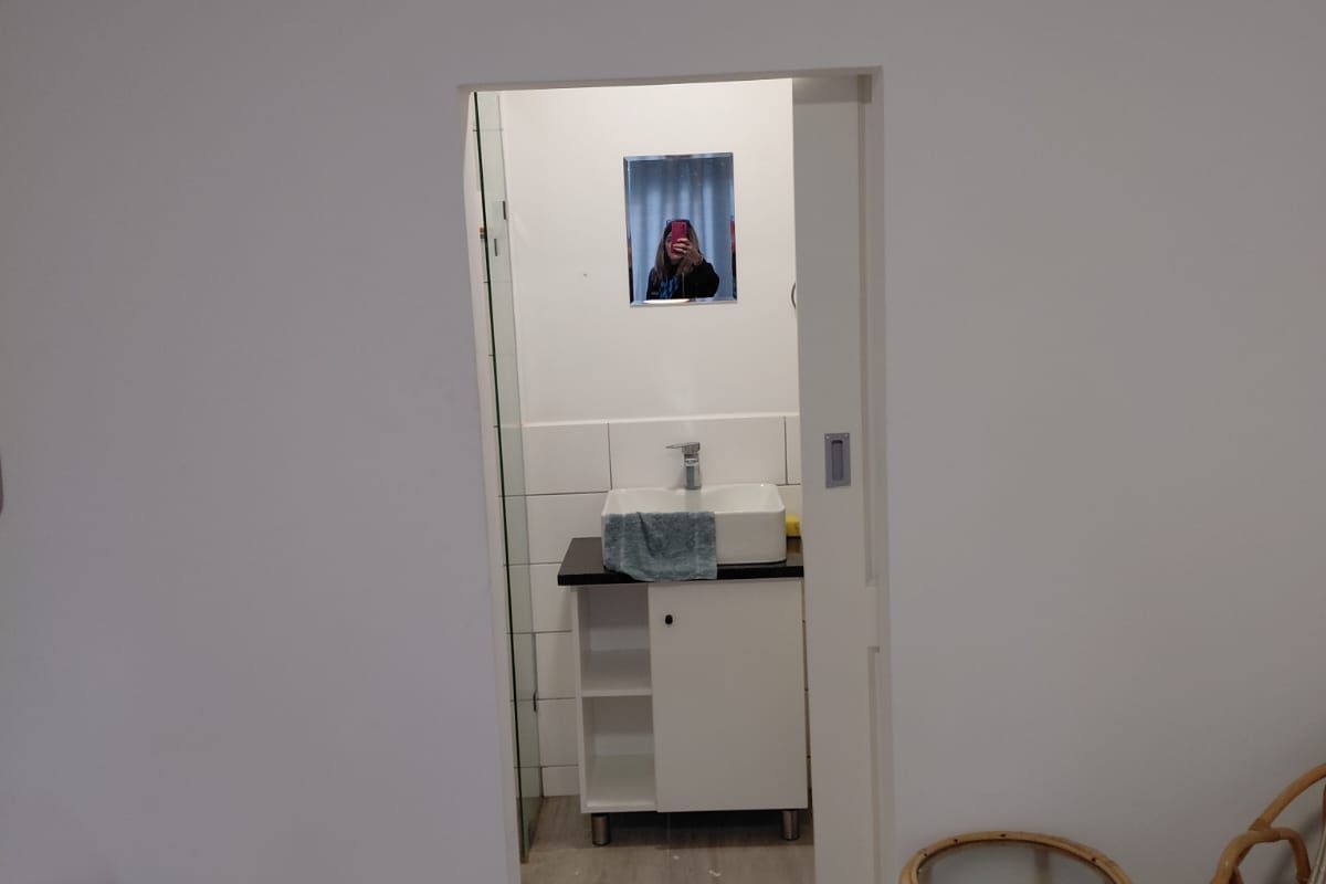 A view into a compact bathroom featuring a modern vessel sink vanity and tiled flooring, accessed via a sliding door.