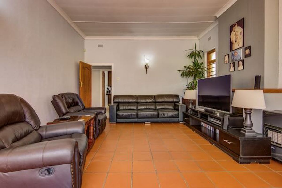 A spacious living room featuring terracotta-style tiled flooring, coved ceilings, and a neutral wall palette, providing a comfortable and functional family living space.