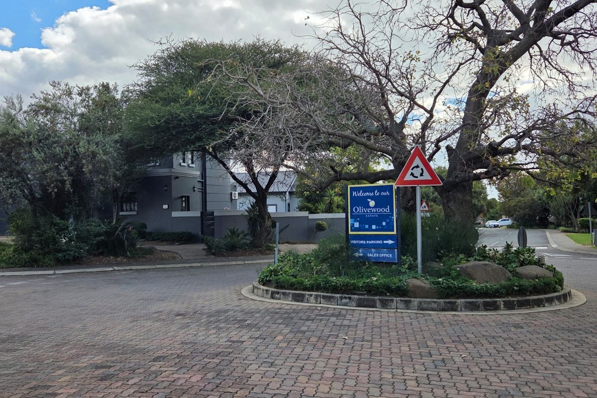 Street view of the Olivewood Estate entrance featuring paved roads, mature trees, and estate signage.