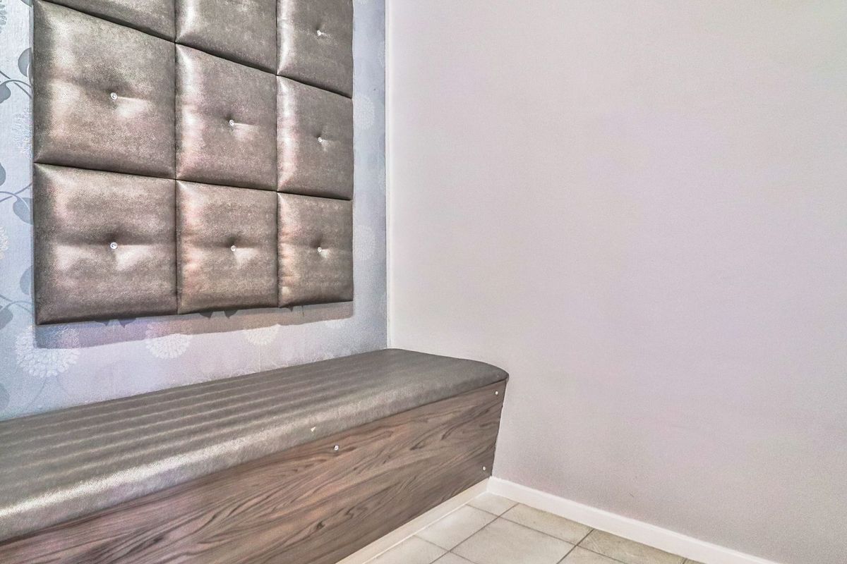 A bedroom area featuring built-in bench seating with integrated storage and decorative upholstered wall paneling.