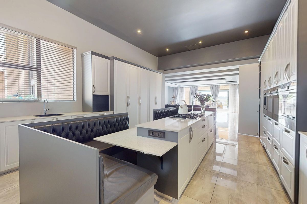 Modern kitchen featuring a large central island with integrated seating, stone countertops, high-end cabinetry, and premium built-in appliances.