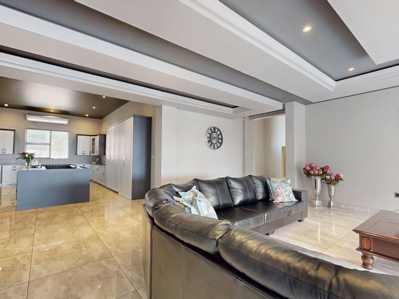 Spacious open-plan living area featuring modern porcelain tiles, a sophisticated recessed ceiling design, and a contemporary kitchen with a central island.