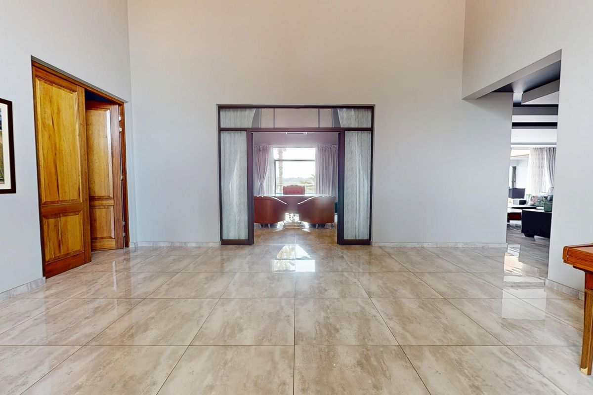 Spacious living area featuring polished tile flooring, high ceilings, and elegant glass-panelled doors leading to an adjacent room.