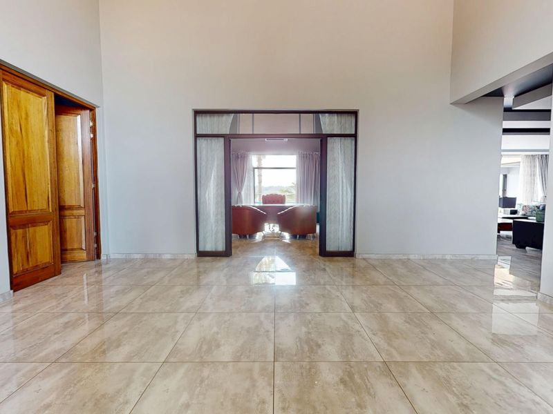 Spacious living area featuring polished tile flooring, high ceilings, and elegant glass-panelled doors leading to an adjacent room.