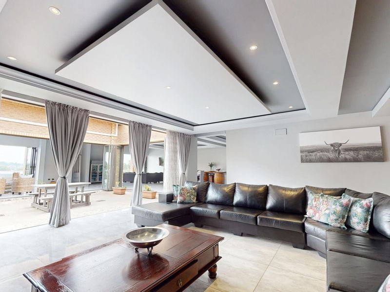 Spacious living room featuring a modern recessed ceiling with downlights and large sliding glass doors that open onto an outdoor patio area.