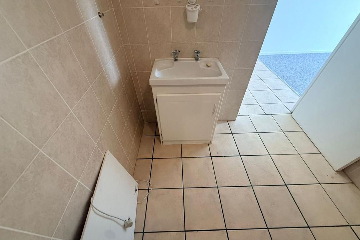 A functional bathroom area featuring a vanity sink with tiled walls and flooring, providing a clean and practical space.