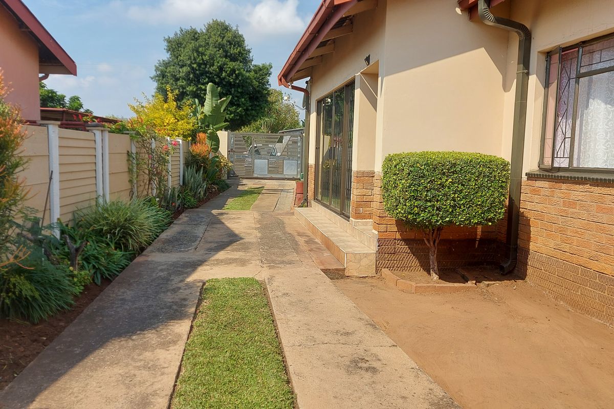 A side view of the property featuring a concrete driveway, brick exterior walls, and a secure gated entrance.