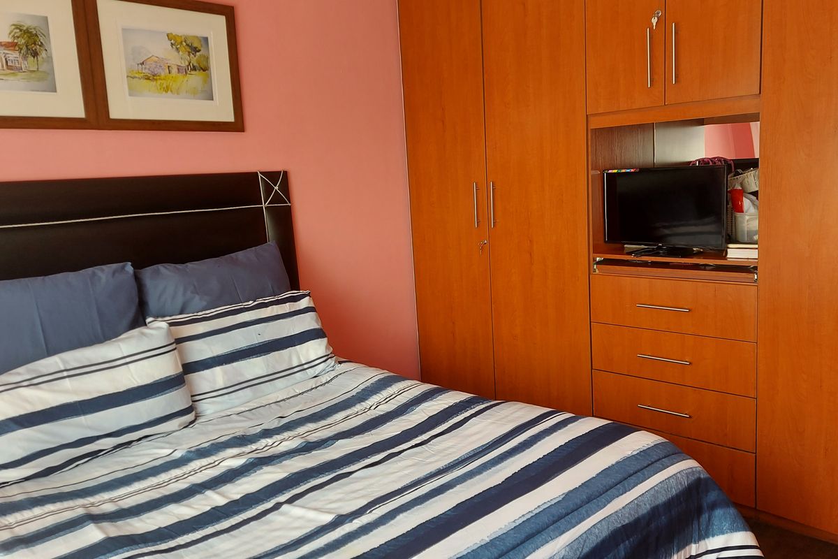 A bedroom featuring built-in wooden cabinetry with integrated storage drawers and wardrobe space.