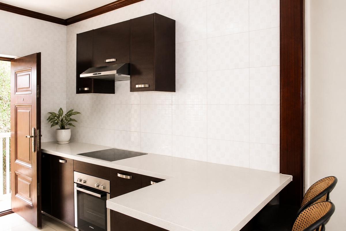 A modern kitchen featuring dark wood cabinetry, stone countertops, a built-in oven, and an electric cooktop with an integrated extractor fan.