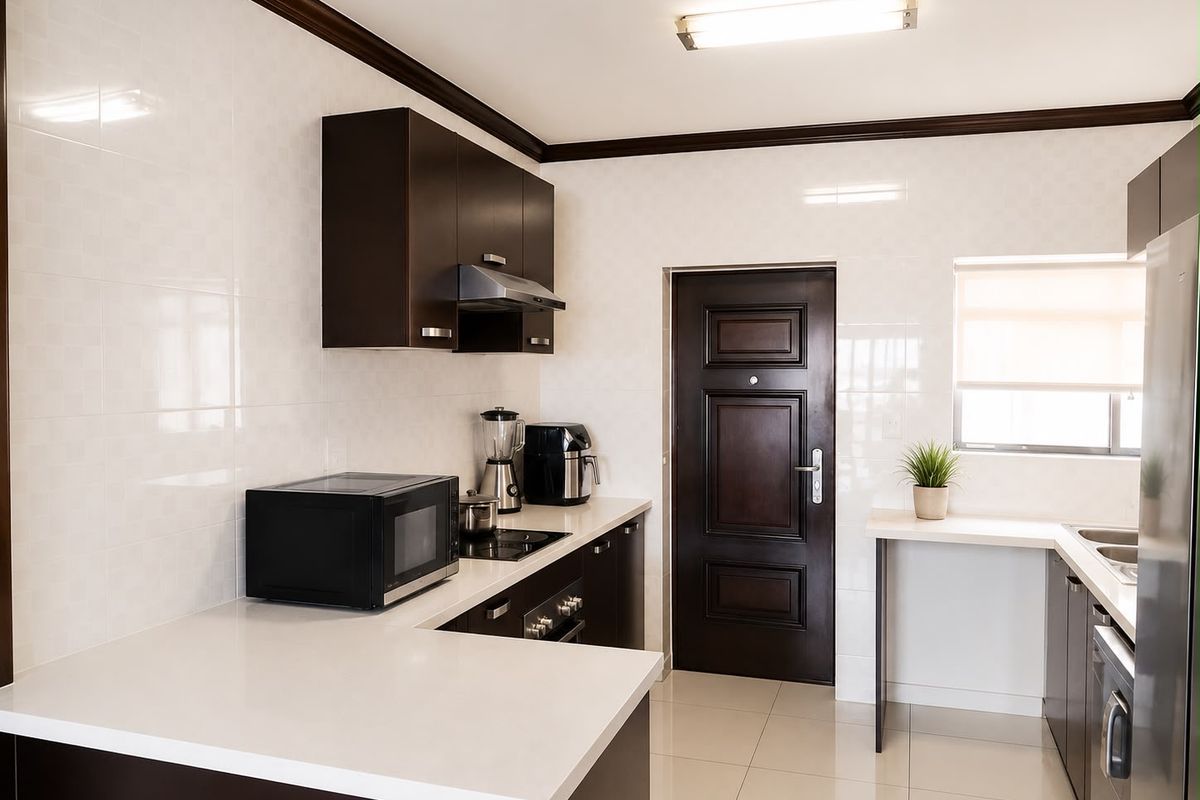 A modern kitchen featuring dark wood cabinetry, stone countertops, integrated appliances, and tiled finishes, providing a clean and functional workspace.