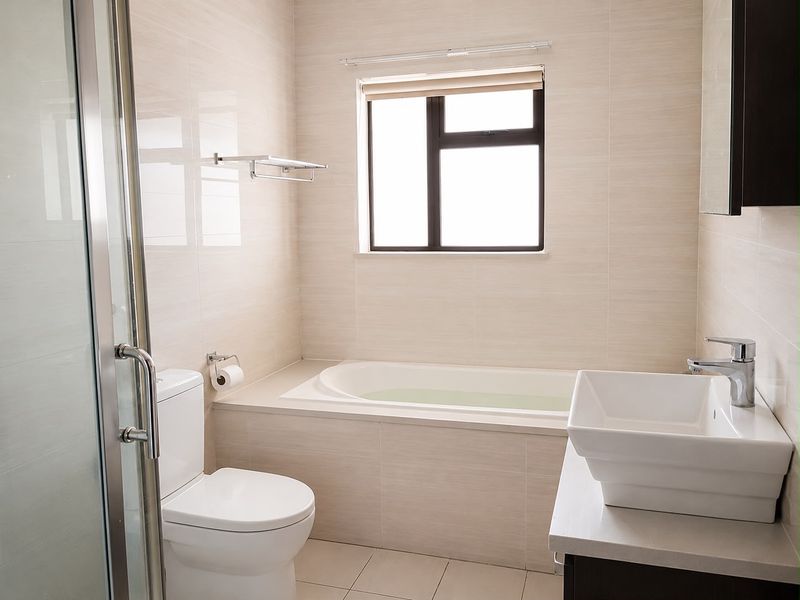 Modern bathroom featuring a built-in bathtub, separate shower enclosure, vessel sink vanity, and neutral wall tiling.
