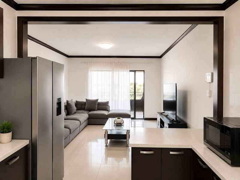 Modern open-plan living area featuring tiled floors, dark wood crown molding, and a seamless transition to a private balcony through sliding glass doors.
