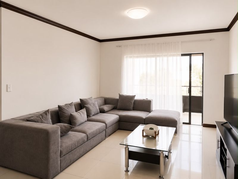A bright and modern living room featuring tiled flooring, crown molding, and a sliding glass door providing access to an outdoor balcony.
