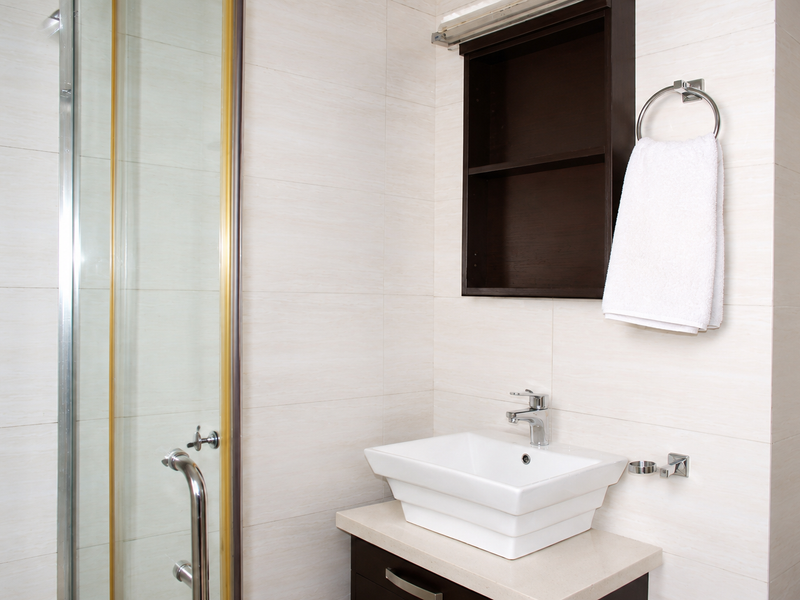 A modern bathroom featuring a glass shower enclosure, a contemporary vessel sink on a vanity cabinet, and convenient wall-mounted storage.