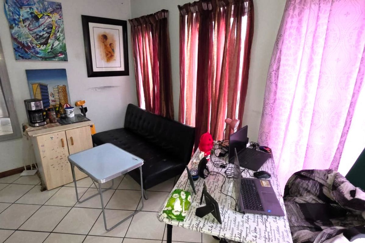 A living area featuring tiled flooring and natural light through window curtains, currently utilized as a multi-purpose space.