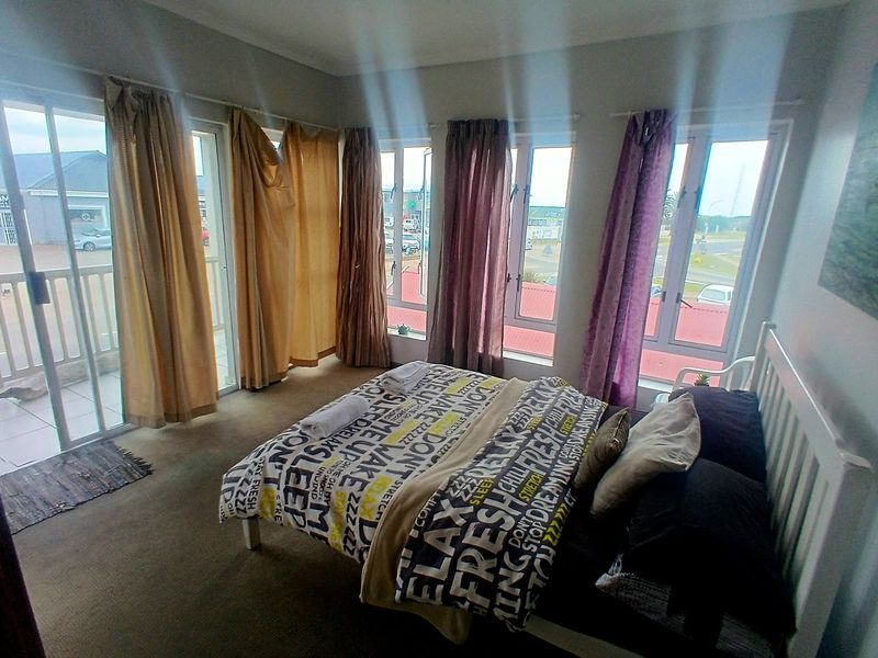 A bedroom featuring carpeted flooring, large windows, and a sliding glass door providing access to an outdoor area.