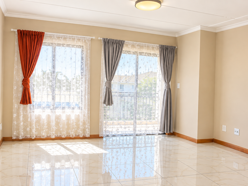 A bright, empty living room featuring polished tiled flooring, neutral walls, and a sliding glass door providing access to an outdoor balcony area.