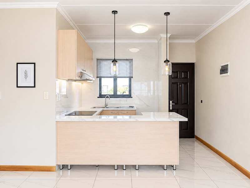 Modern kitchen featuring light wood cabinetry, marble-look countertops, integrated hob, and sleek porcelain tile flooring in a clean, open-plan layout.