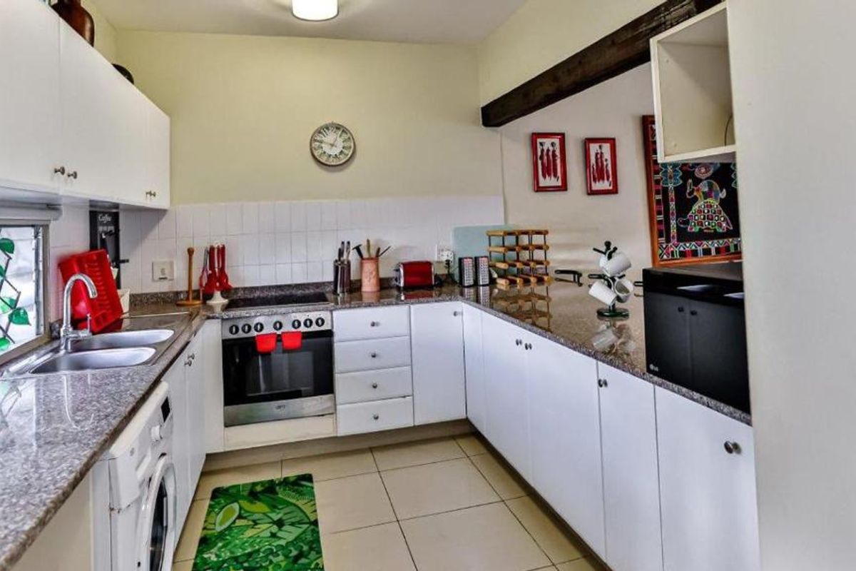 Functional kitchen featuring granite countertops, built-in cabinetry, an electric hob, oven, and double basin sink with tiled flooring.