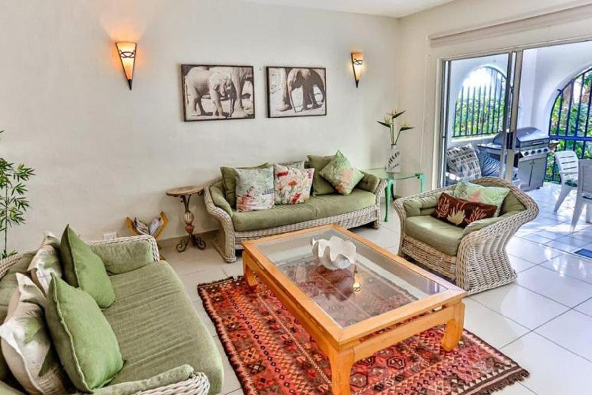 A bright living room featuring tiled flooring and large sliding glass doors that provide direct access to an outdoor patio area.