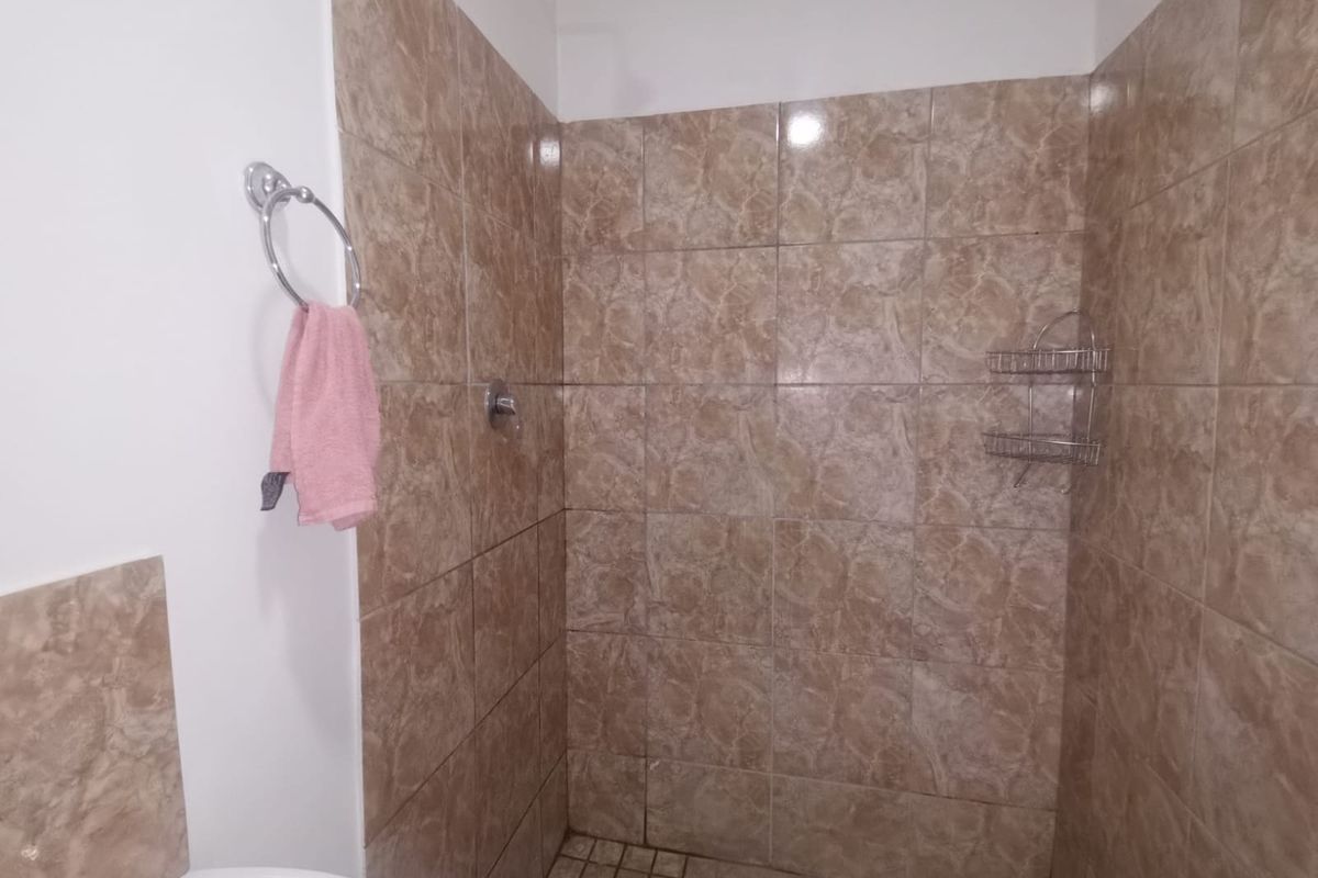 A functional bathroom shower area featuring floor-to-ceiling brown marble-effect wall tiles and a tiled shower floor.