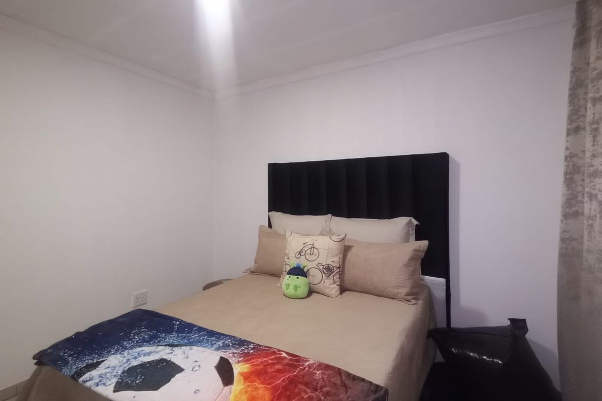 A simple bedroom featuring neutral walls and a black headboard, providing a clean and functional space.