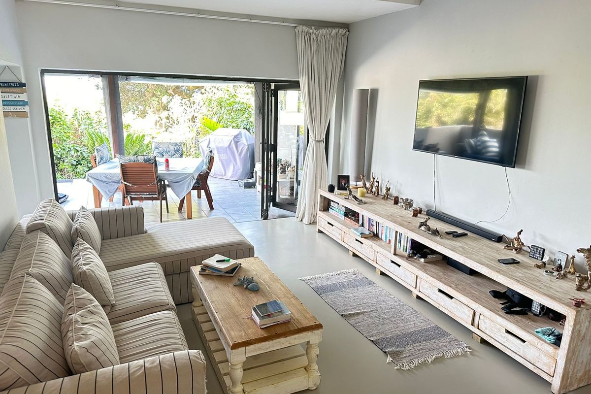 Spacious living room featuring smooth concrete flooring and large bi-fold doors that open onto a covered patio area.