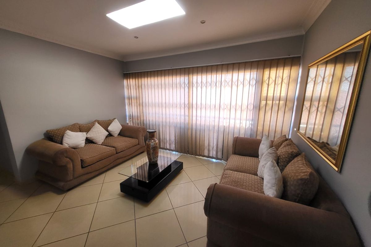 A living room featuring tiled flooring, recessed ceiling lighting, and a large sliding glass door with an integrated security gate.