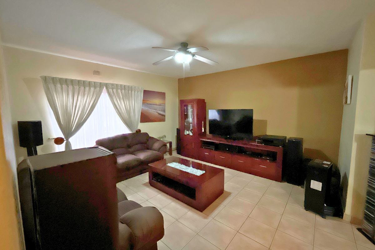 A comfortable living room featuring tiled flooring and a ceiling fan, providing a functional and well-maintained space for relaxation.