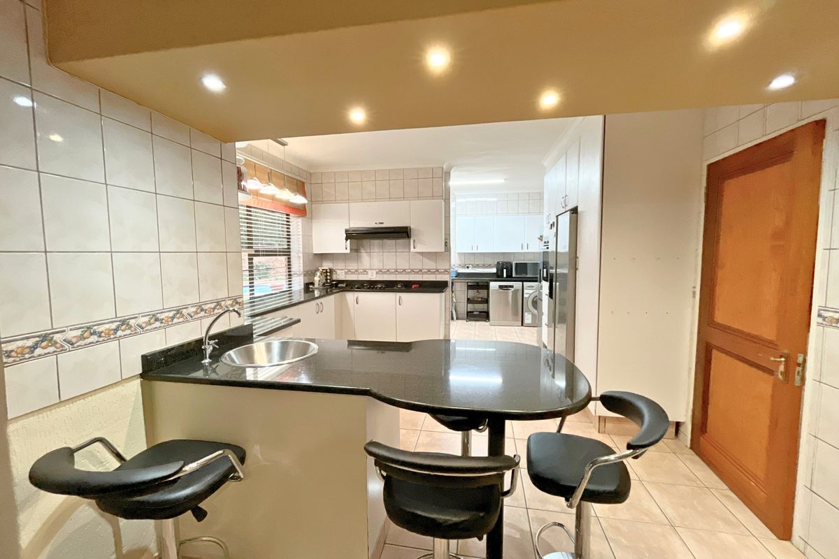 Functional kitchen featuring granite countertops, ample built-in cabinetry, a tiled backsplash, and a breakfast bar area with integrated sink.
