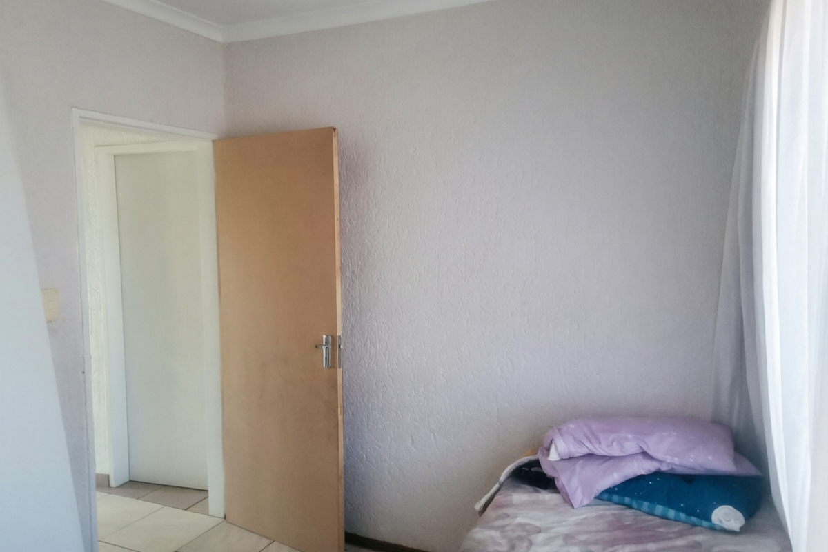 A simple bedroom featuring tiled flooring and a standard interior door, providing a functional and neutral space.