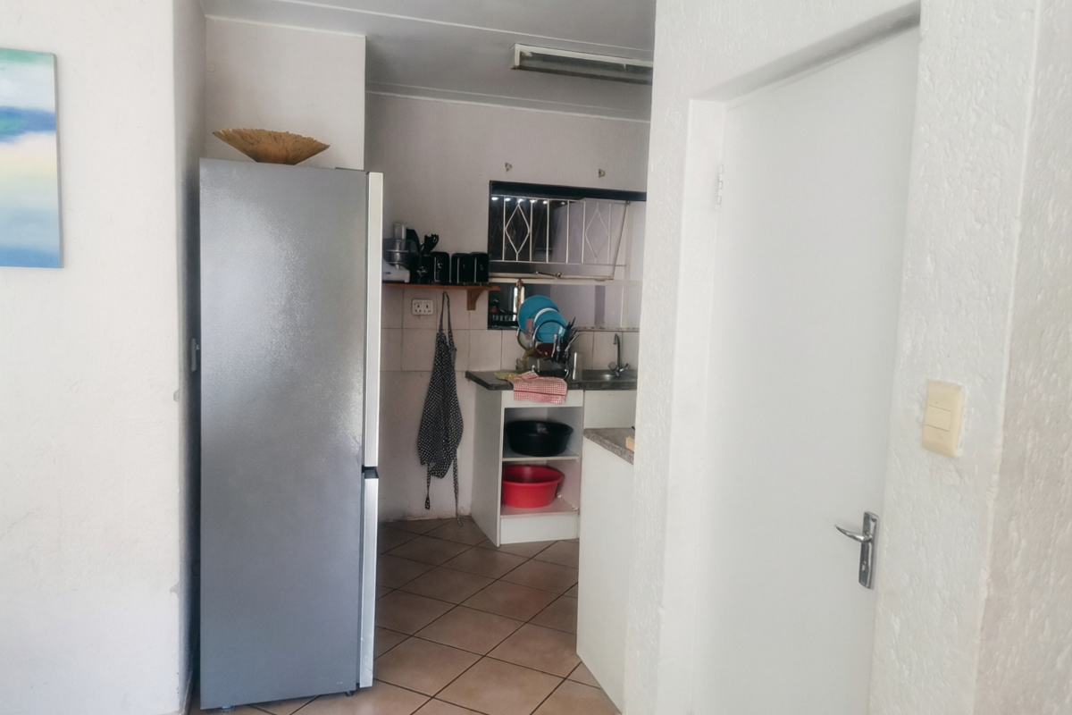 A functional kitchen area featuring tiled flooring, built-in cabinetry, and a sink, providing a practical workspace within the townhouse.
