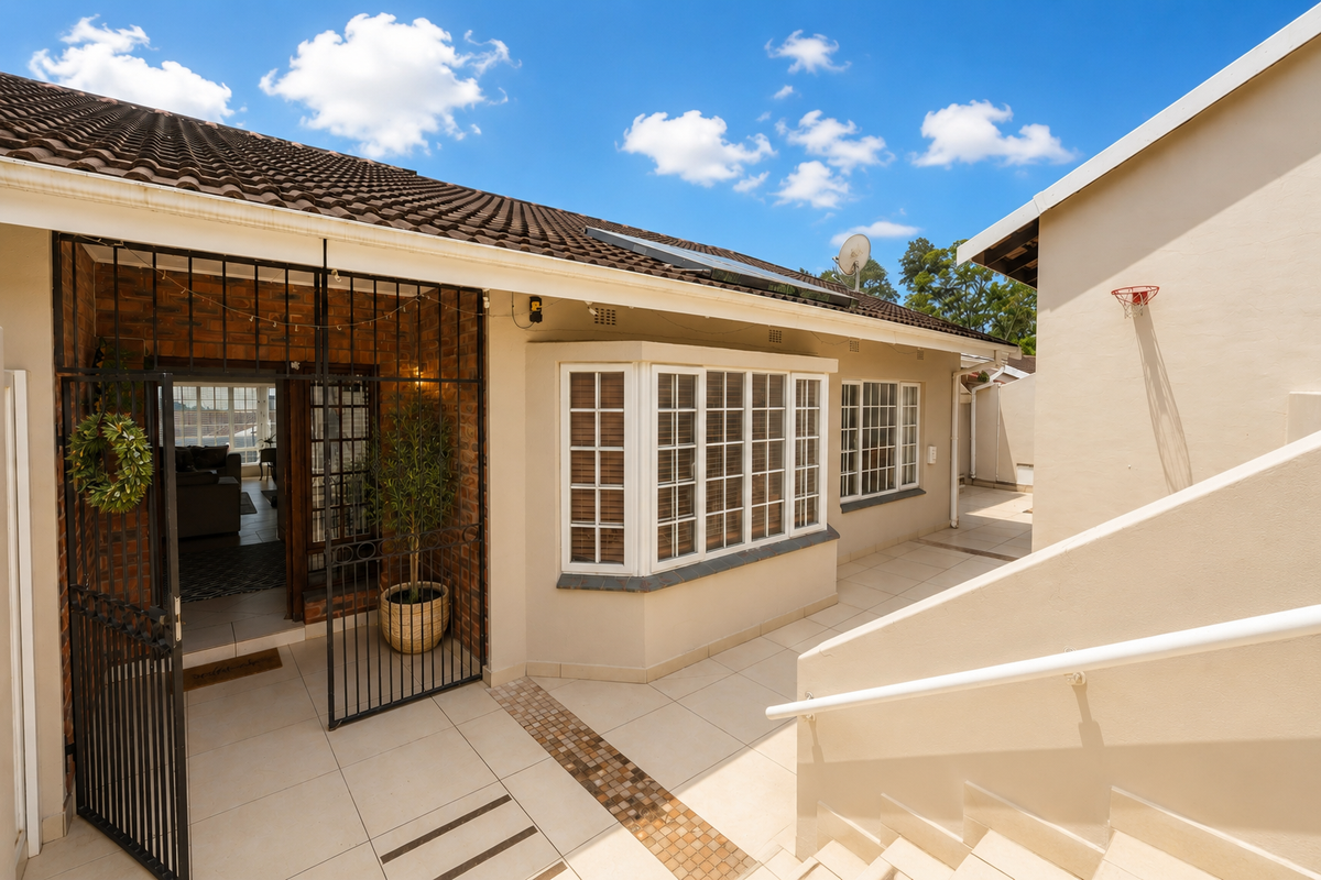 A well-maintained rear patio area featuring tiled flooring, a bay window, and secure gated access to the interior living space.