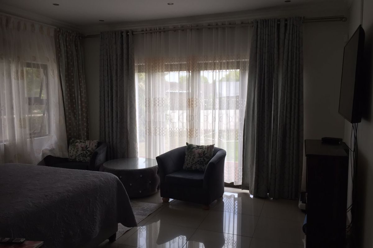 A bedroom featuring tiled flooring, recessed ceiling lighting, and large sliding glass doors with floor-to-ceiling curtains providing access to the exterior.