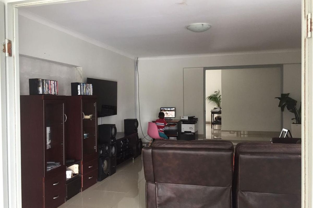 A spacious living room featuring tiled flooring and neutral walls, providing a functional area for relaxation and entertainment.